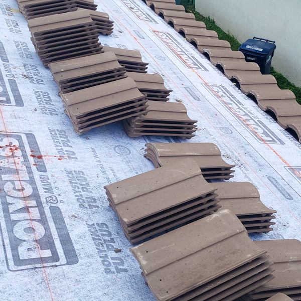 Brown barrel tiles stacked on a roof.