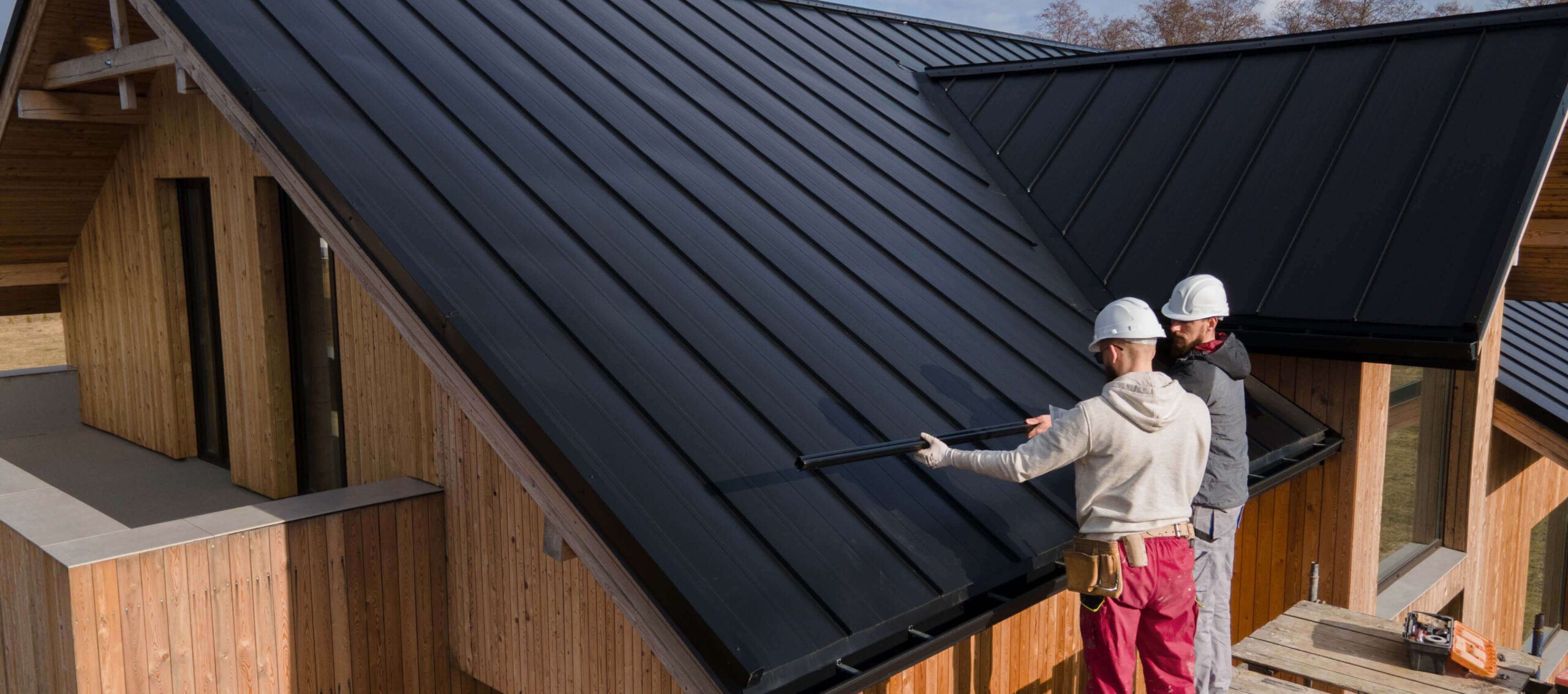 Roofing worker repairing a black metal roof.