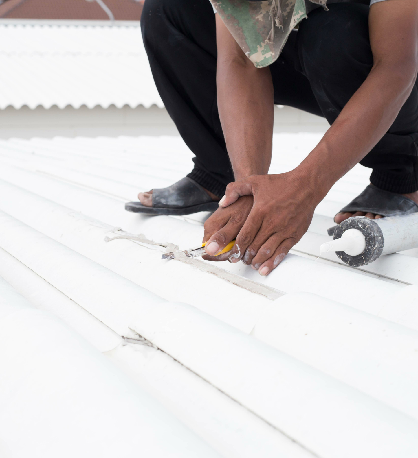 A worker applying white silicone coating to a roof.